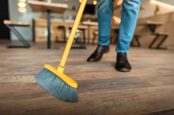 a person using a broom for cleaning