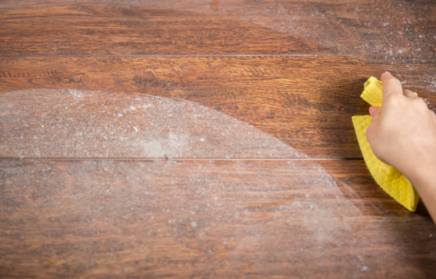 a person removing dust from the wooden floor