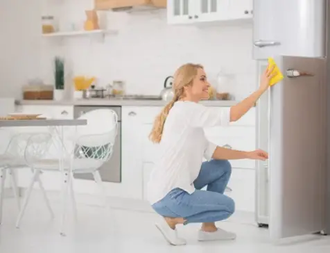a woman cleaning the fridge in the kitchen