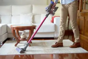 A man vacuuming a carpet with a dyson