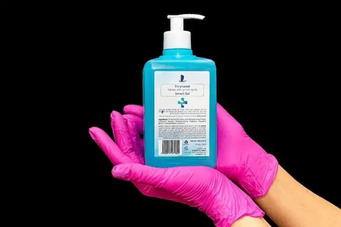 pink rubber gloves on hands with a bottle of lotion